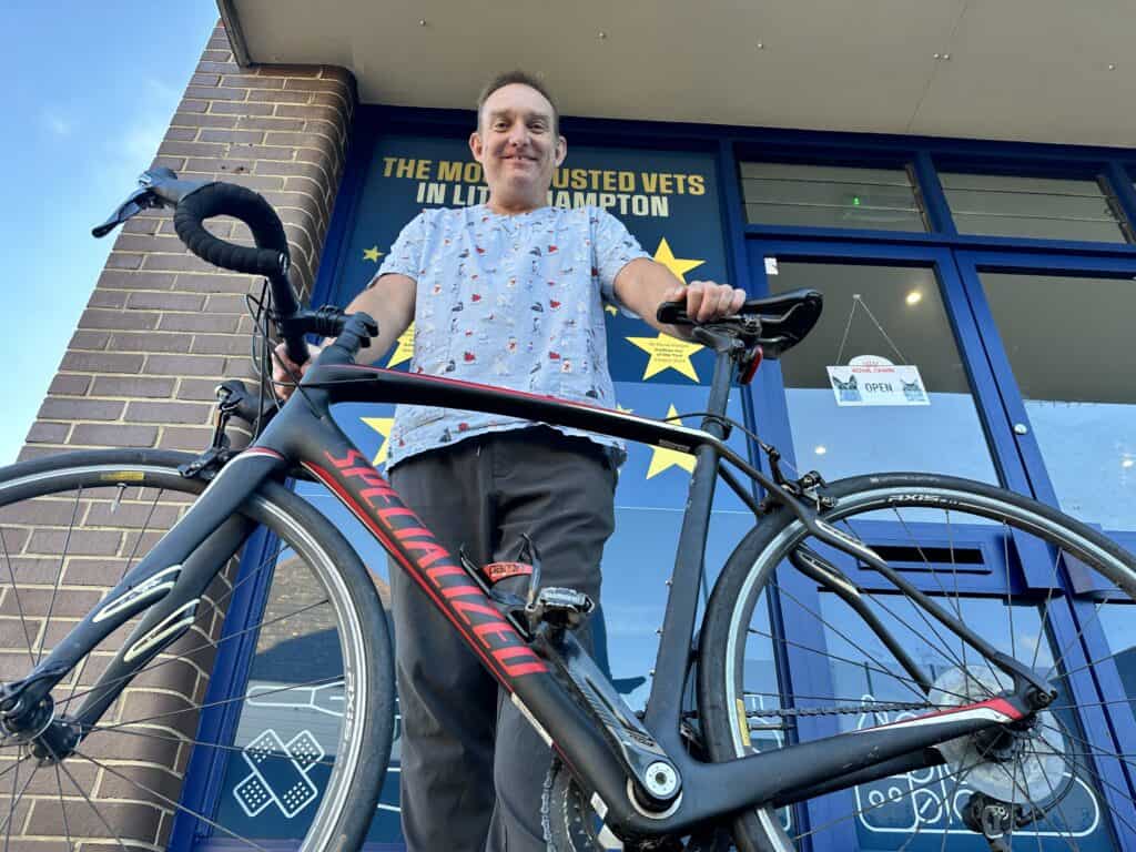 Dr David Hodges leaning on bike outside Stellar Vet Clinc in Littlehampton